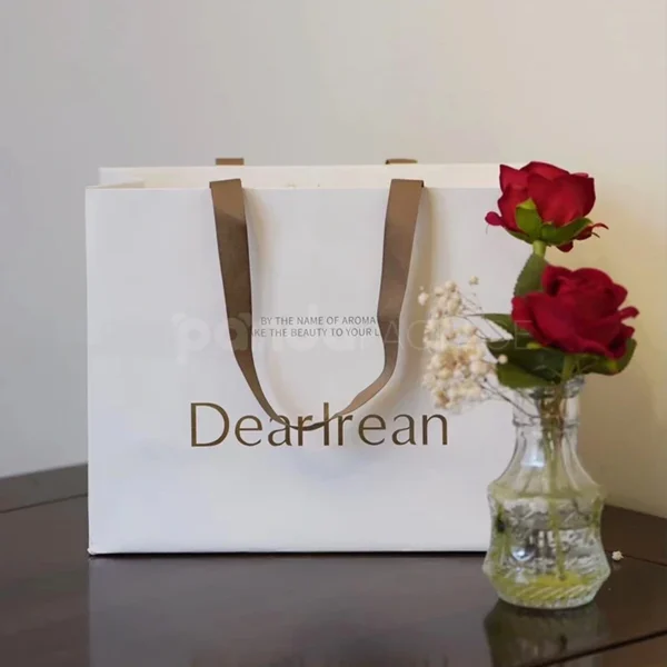 Elegant White Gift Bag with Gold Foil Logo and Brown Handles