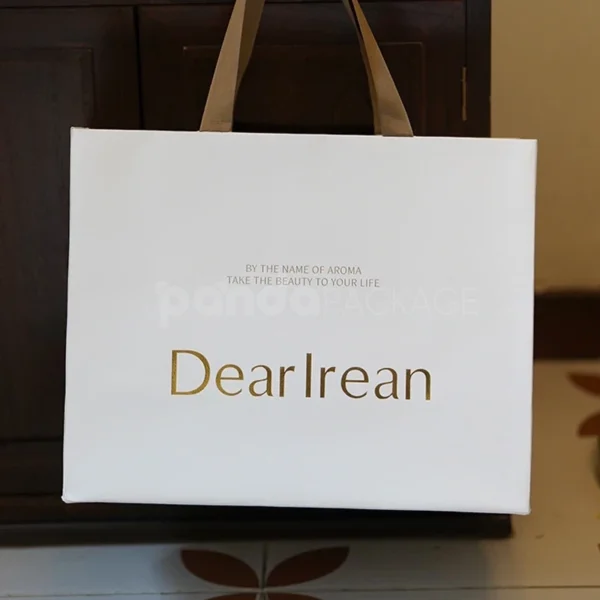 Elegant White Gift Bag with Gold Foil Logo and Brown Handles