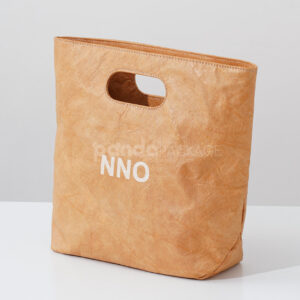 Reusable kraft-look non-woven tote bag with die-cut handles on display