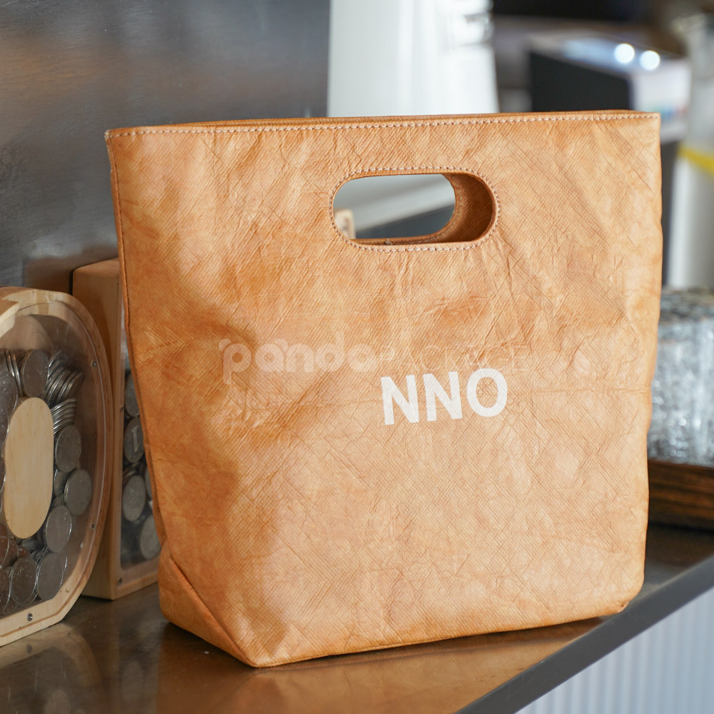 Reusable kraft-look non-woven tote bag with die-cut handles on display