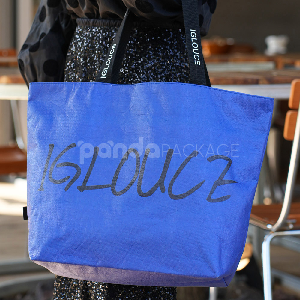 Blue paper tote bag with black branded handles