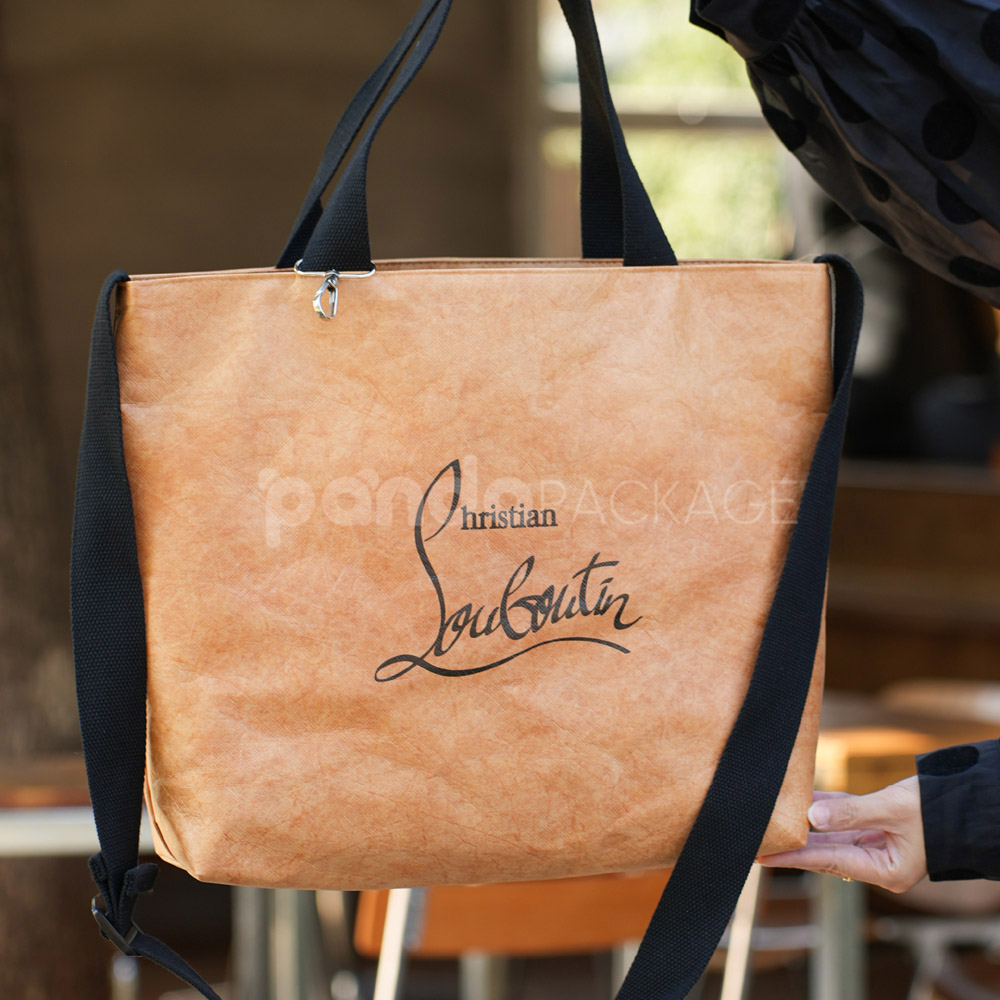 Brown kraft paper tote bag with black handles and shoulder strap