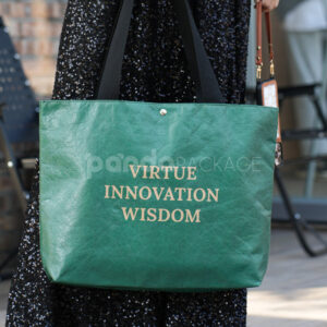 green paper tote bag with inspirational text and black handles