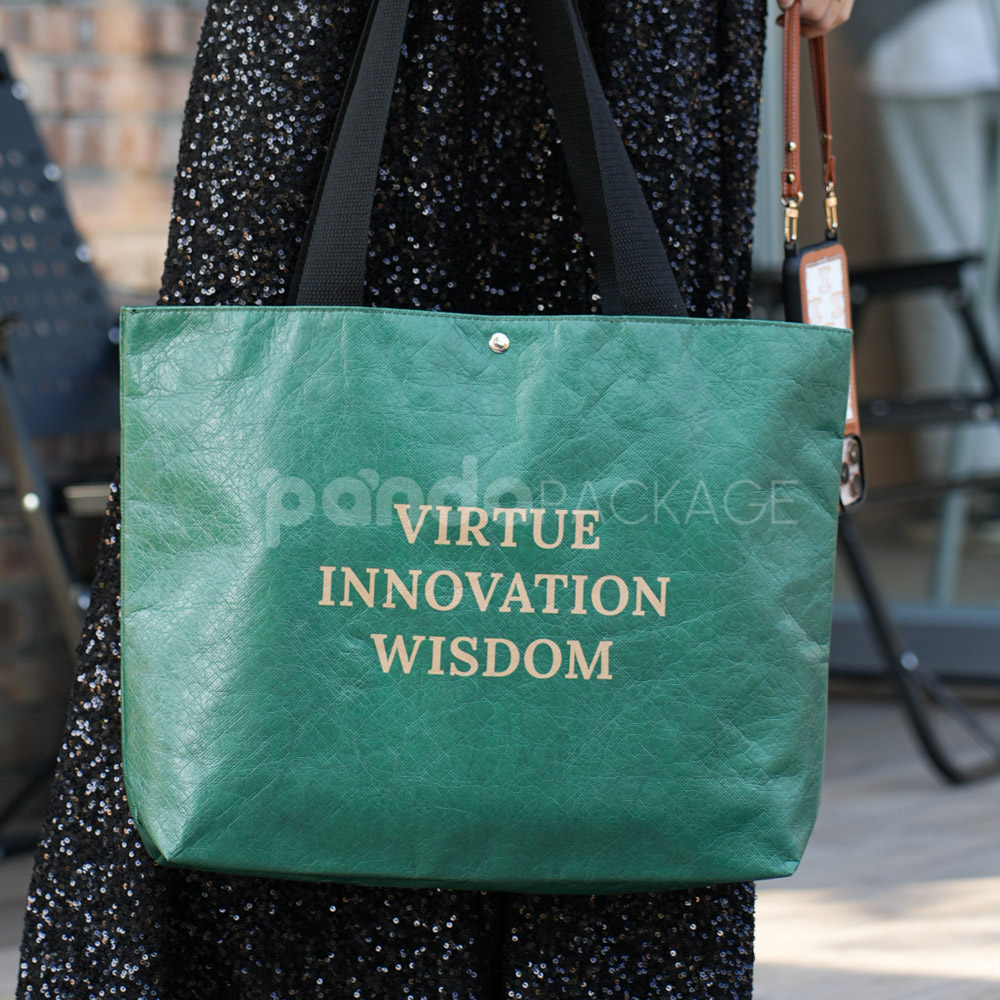 green paper tote bag with inspirational text and black handles