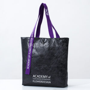 black paper tote bag with purple woven logo handles