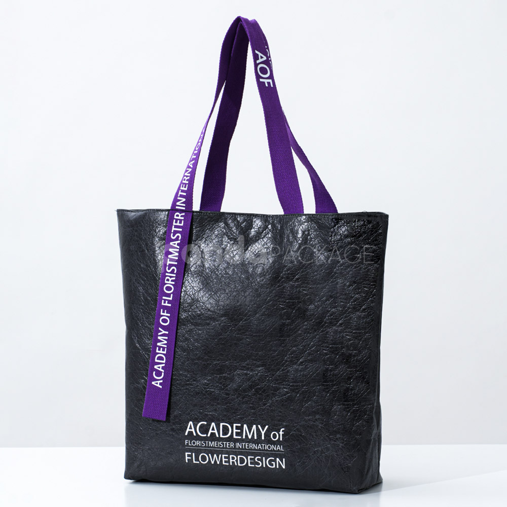 black paper tote bag with purple woven logo handles