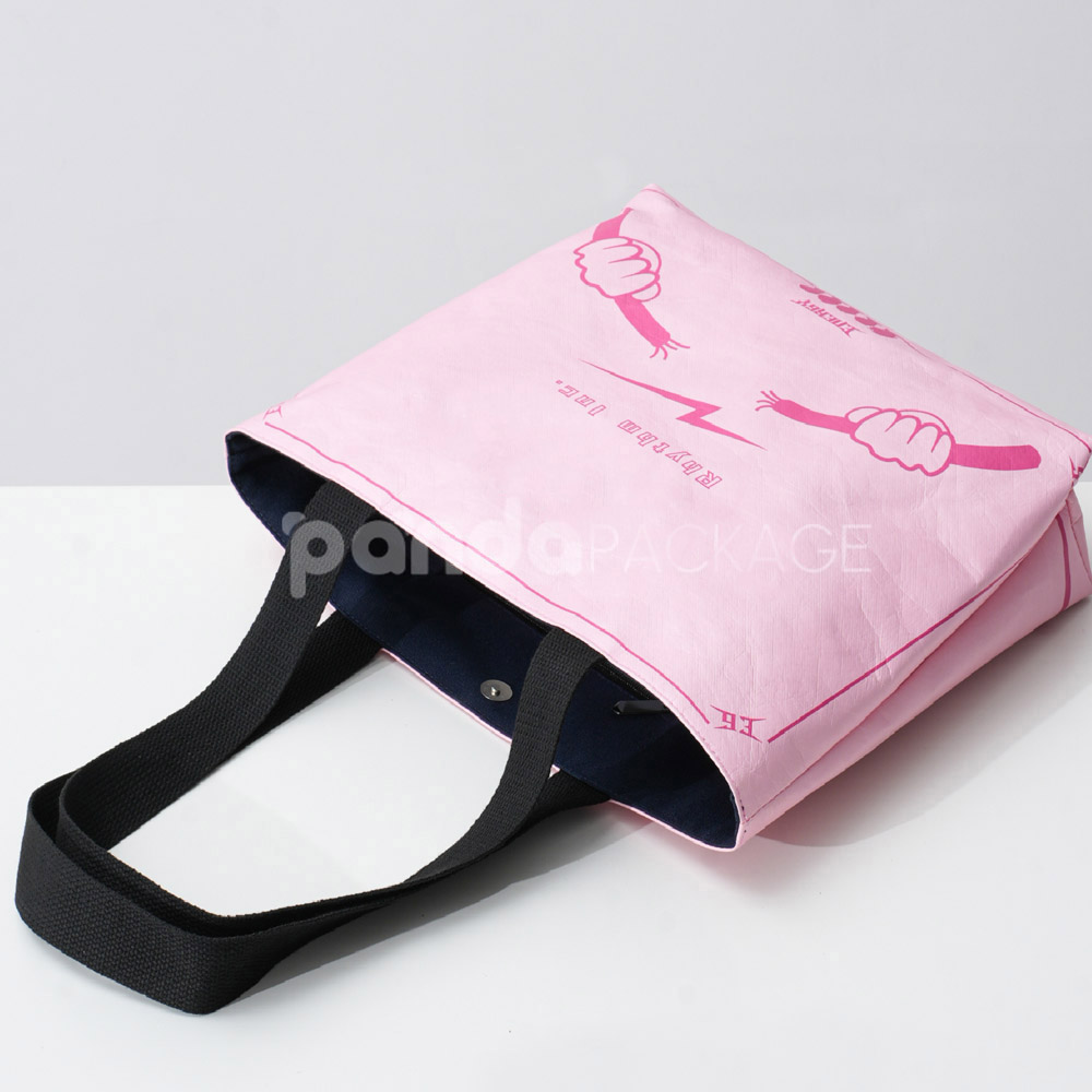 Pink paper tote bag with graffiti-style print and black handles