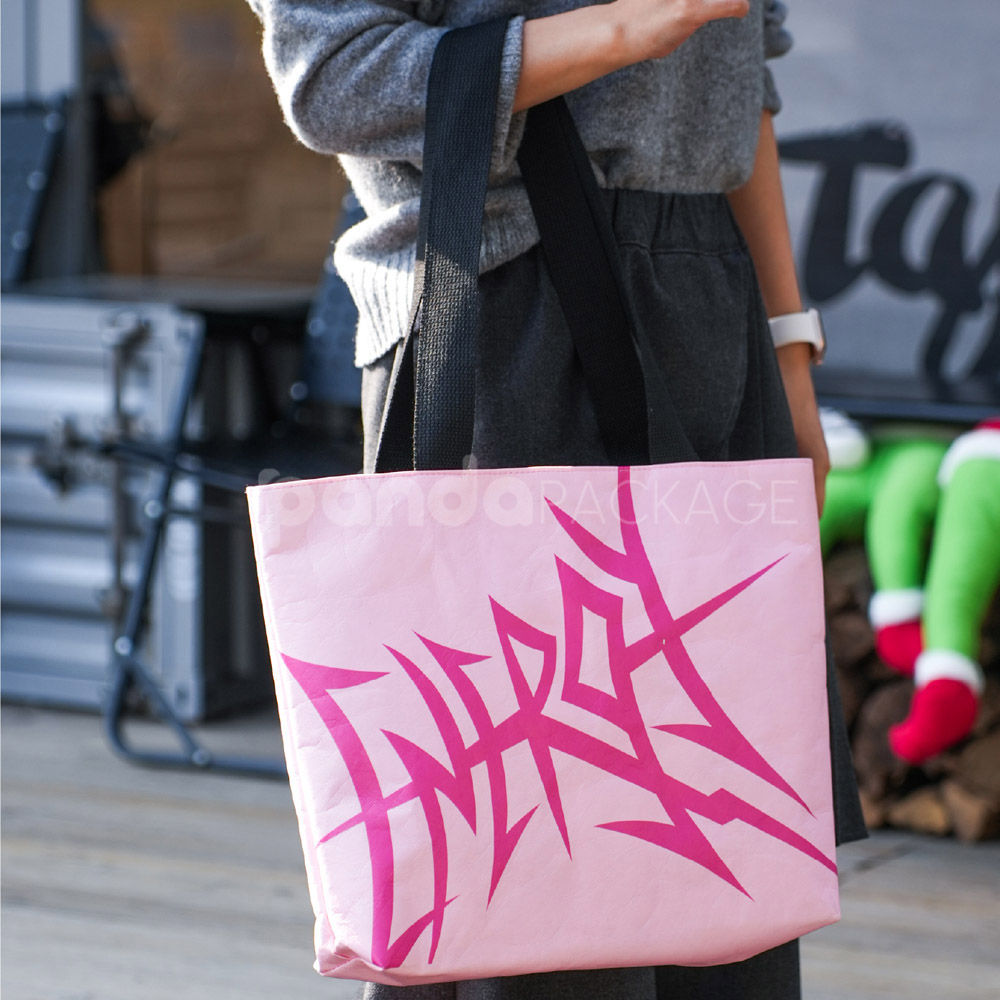 Pink paper tote bag with graffiti-style print and black handles