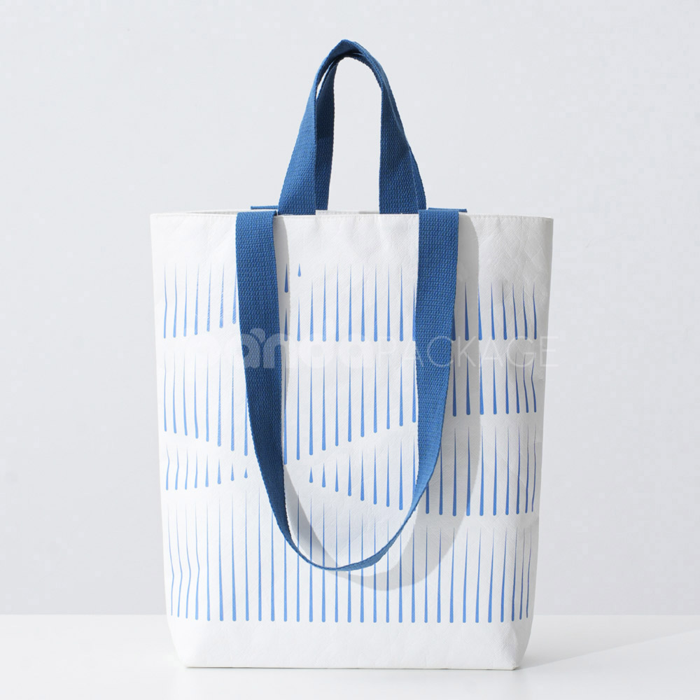 Ivory tote bag with blue woven handles and abstract line pattern