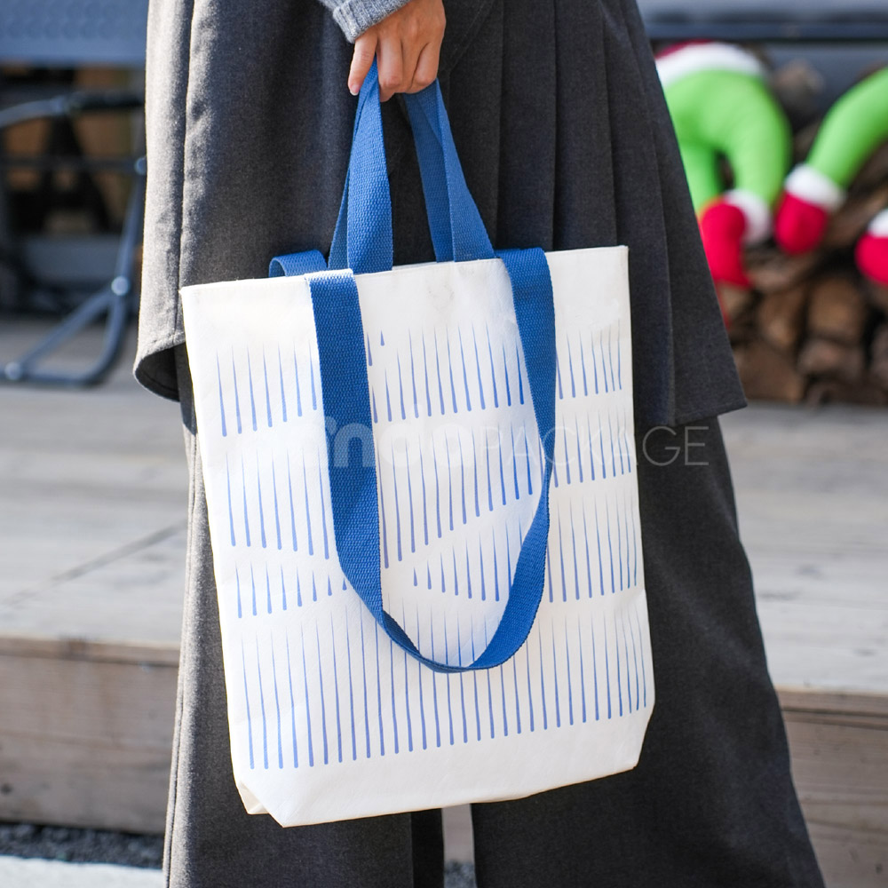Ivory tote bag with blue woven handles and abstract line pattern