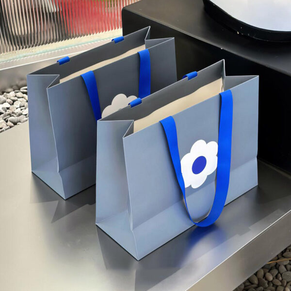 Gray Apparel Shopping Bag with Blue Handles and Flower Print