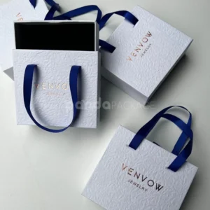 textured white rigid drawer box with blue satin ribbon handles and foil stamping