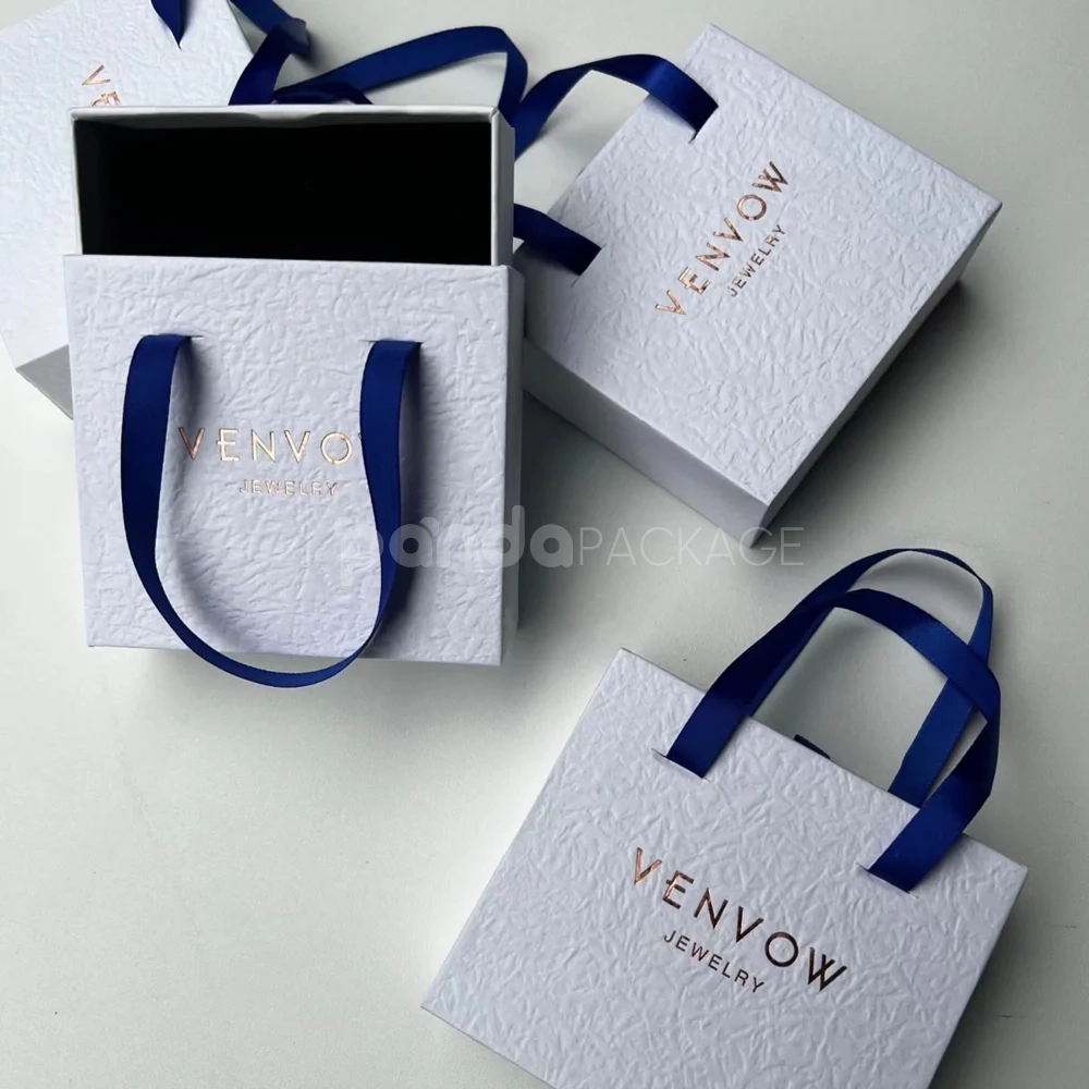 textured white rigid drawer box with blue satin ribbon handles and foil stamping