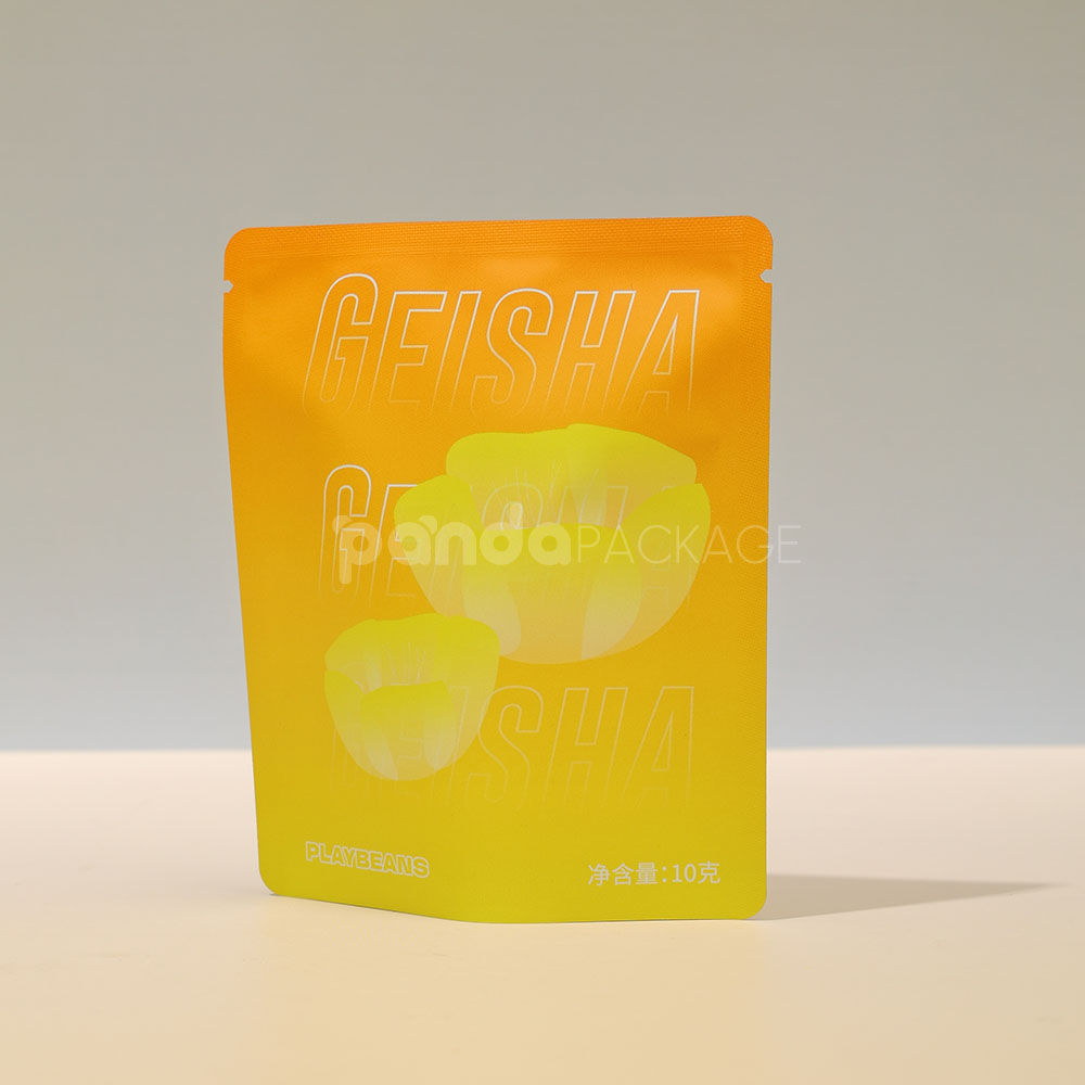 small gradient yellow–orange stand-up coffee pouch with matte surface