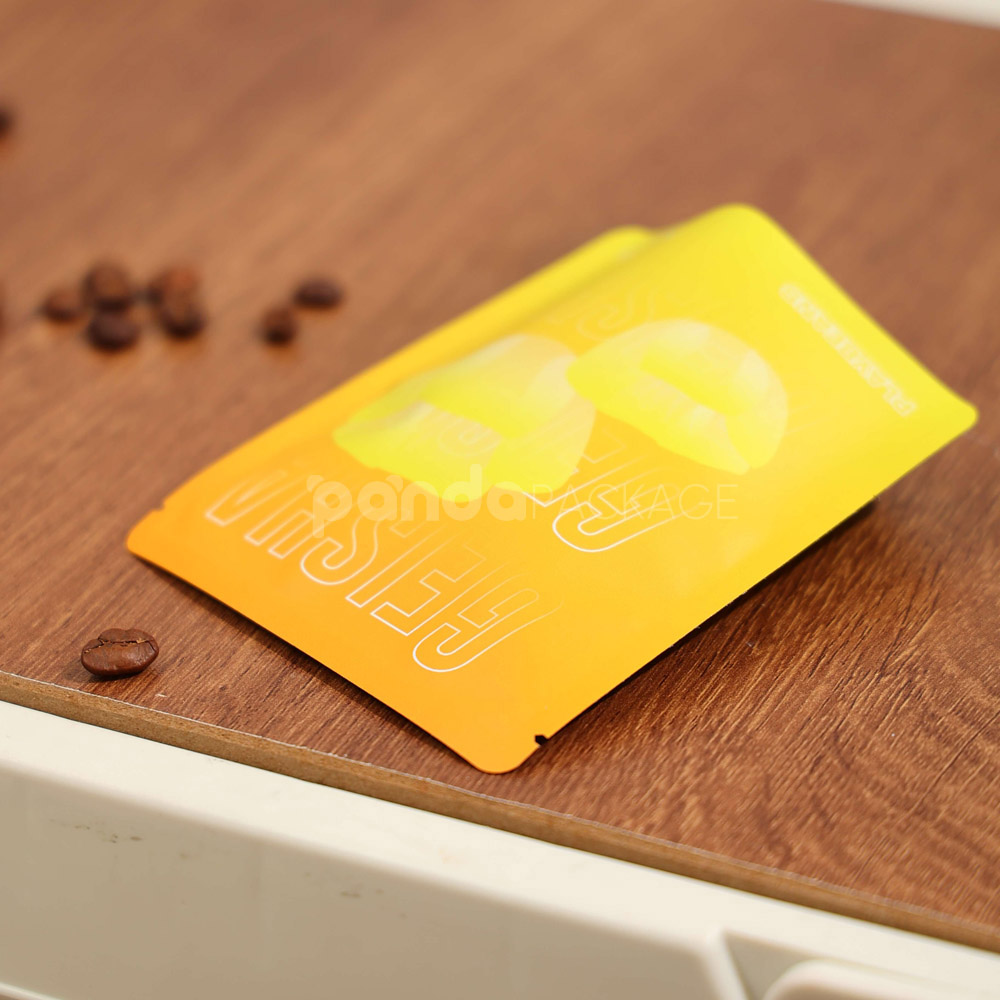 small gradient yellow–orange stand-up coffee pouch with matte surface