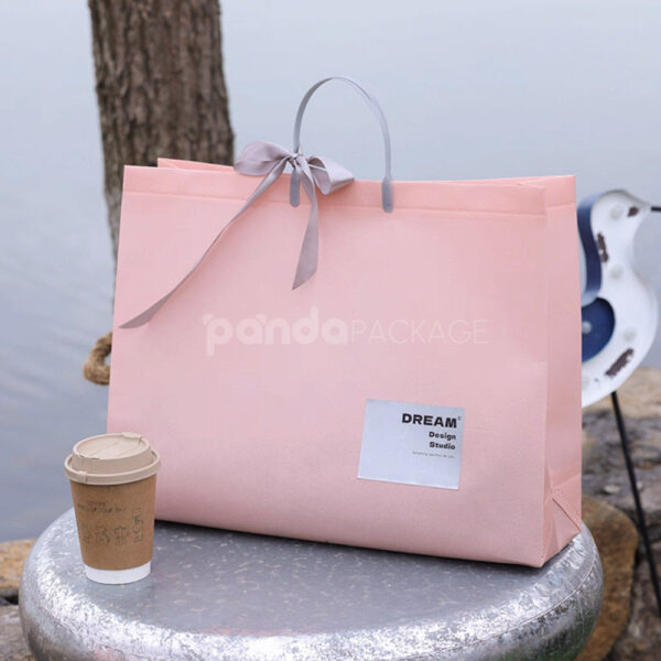 Laminated Non-Woven Tote Bags with Plastic Handles and Ribbon Bow for Apparel Packaging