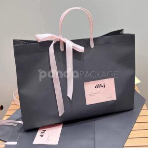 laminated non-woven tote bags with plastic handles and ribbon bow for apparel packaging in customizable colors and sizes