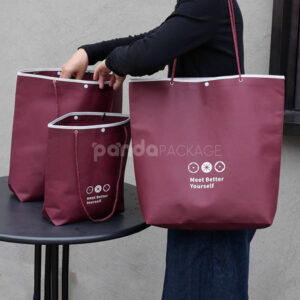 tapered non-woven tote bags with rope handles and piping edges, available in multiple colors and custom sizes for apparel packaging