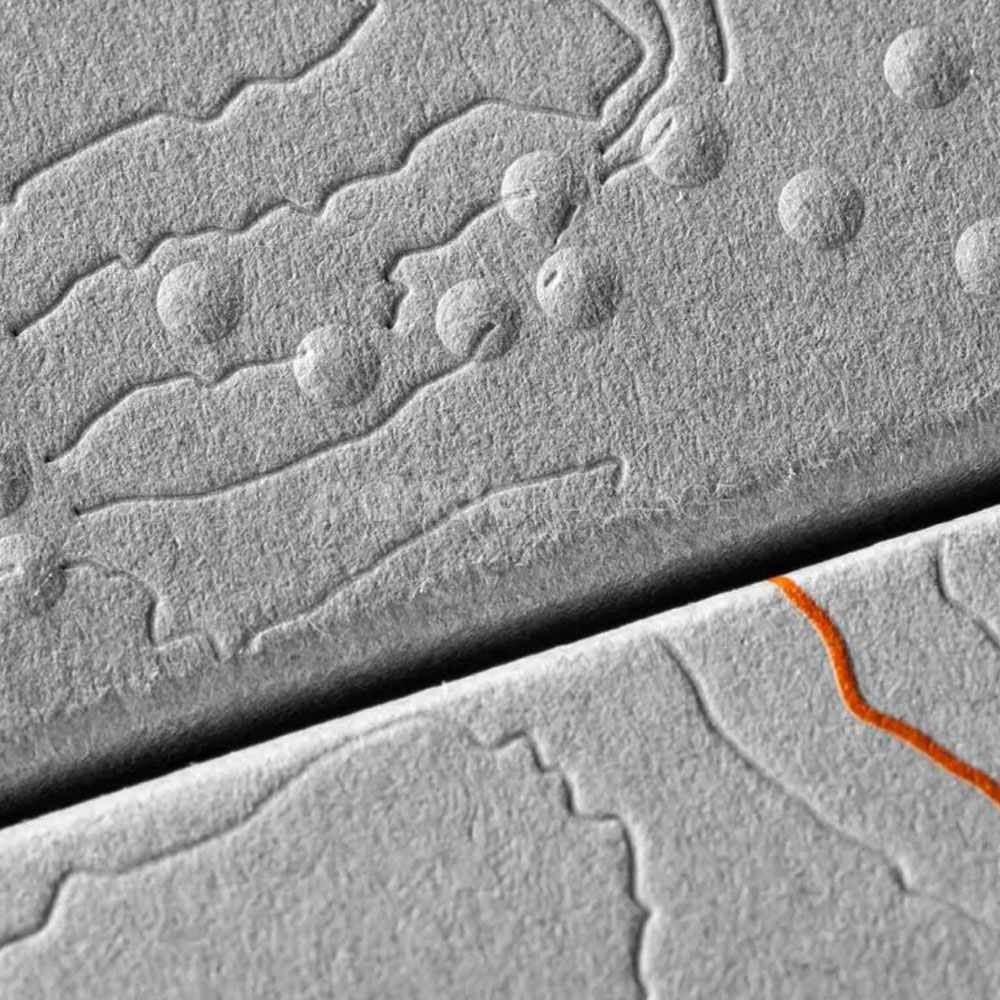 luxury textured grey paperboard box for skincare packaging with embossed terrain pattern and orange foil line details