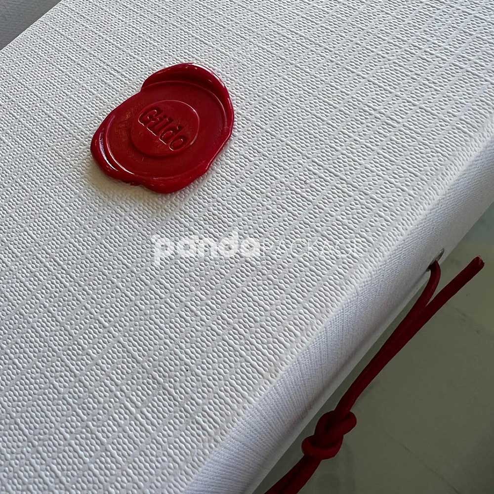 rigid book-style wine packaging box with textured paper surface and wax seal elastic closure for premium red wine bottles