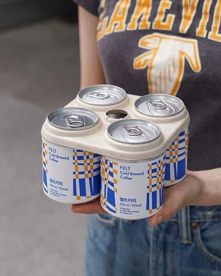 Person holding a moulded-fibre beverage carrier
